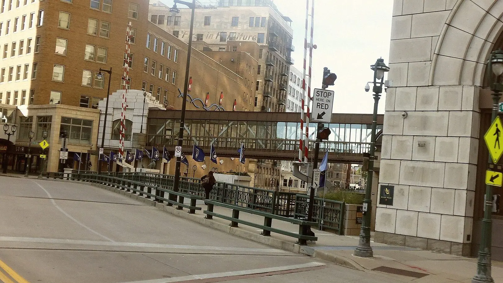 Blue Milwaukee Brewers flags with the team's ball-in-glove logo hanging from light poles along the Wisconsin Avenue Bridge in downtown Milwaukee