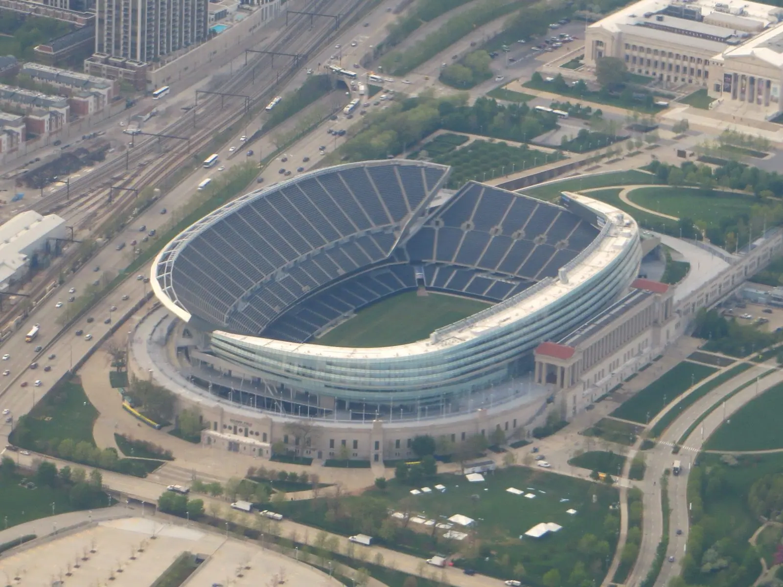 Aerial view of Soldier Field in Chicago, a stadium with a curved glass-and-steel bowl set inside classical colonnades, next to Lake Shore Drive
