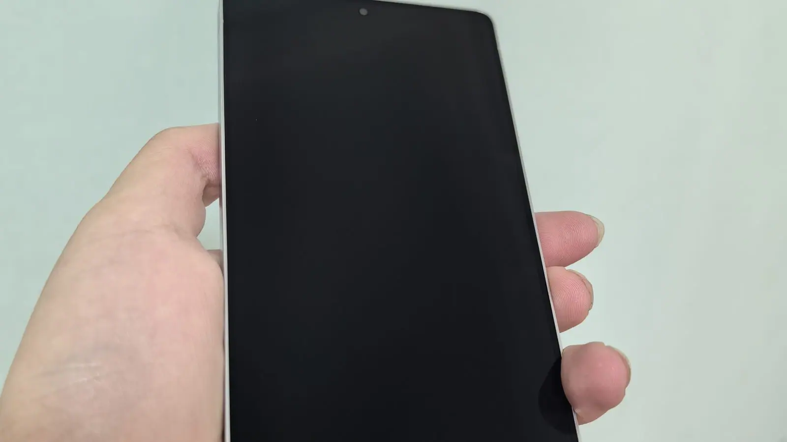 A hand holding a Samsung Galaxy S25 Ultra smartphone with its screen turned off